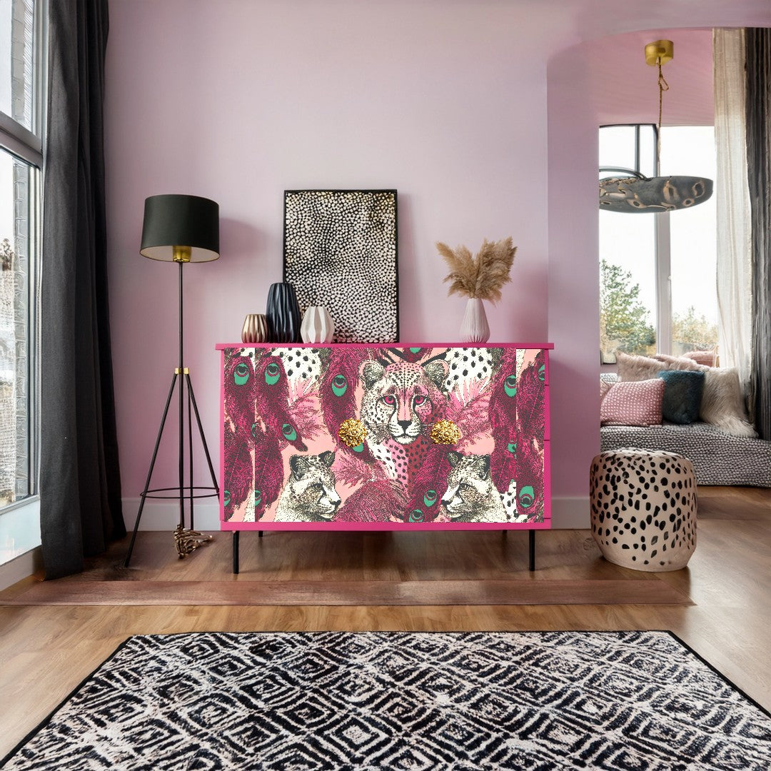 a vibrant and stylish living room with a pink and black cheetah print cabinet as the focal point. The cabinet has a striking design with a pattern of leopards and peacocks, adding a touch of wild beauty to the space. The room is adorned with a large window, allowing natural light to flood in and illuminate the colorful decor. A black floor lamp stands nearby, and a patterned rug covers the floor, complementing the bold design of the cabinet.
